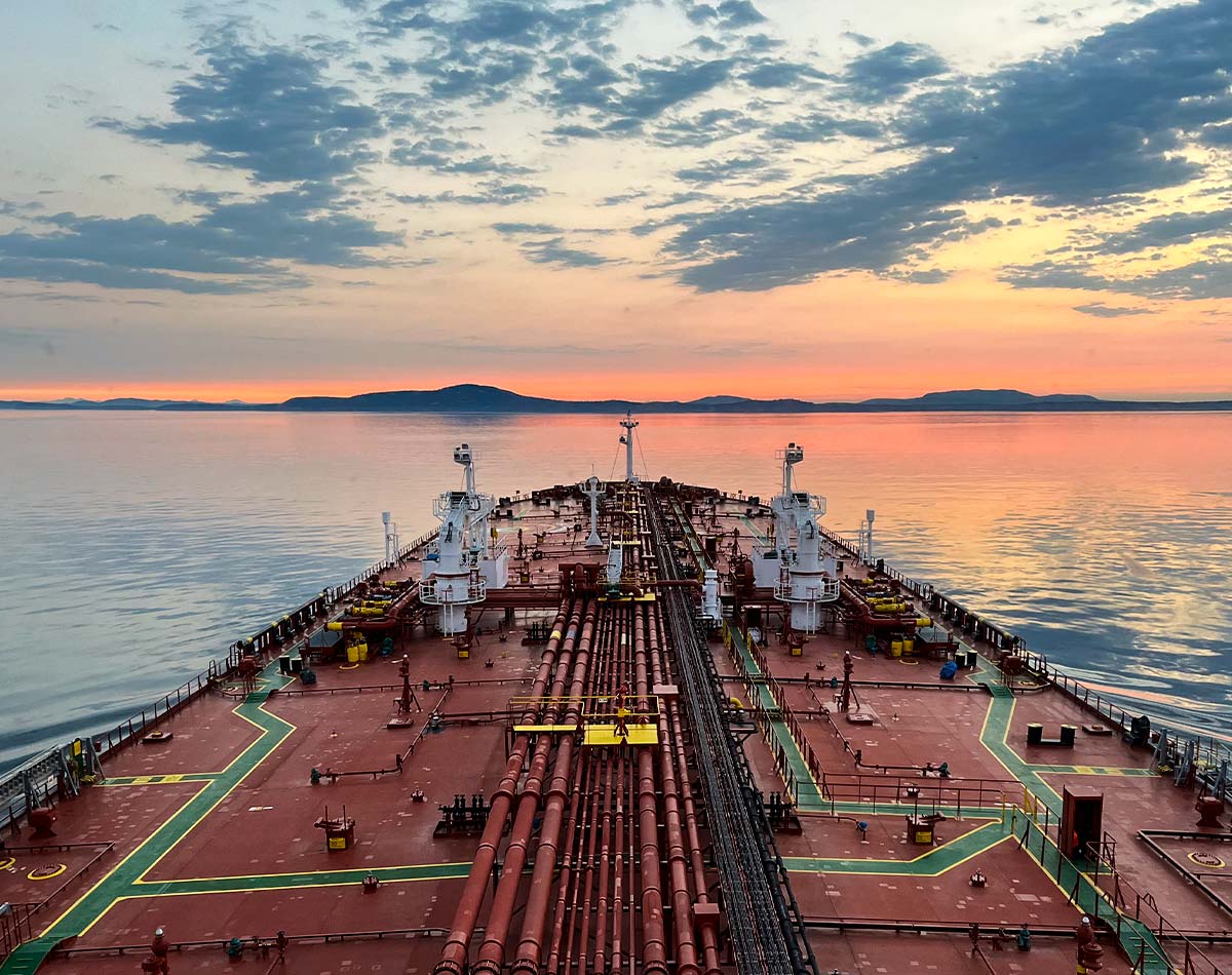 We're the first line of defense for safer waters ship heading out to open water with a sunset in the distance