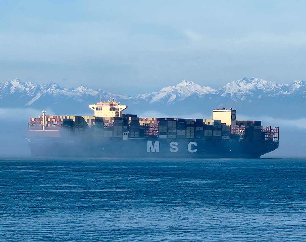 vessel moving through the water with snowcapped mountains in the background